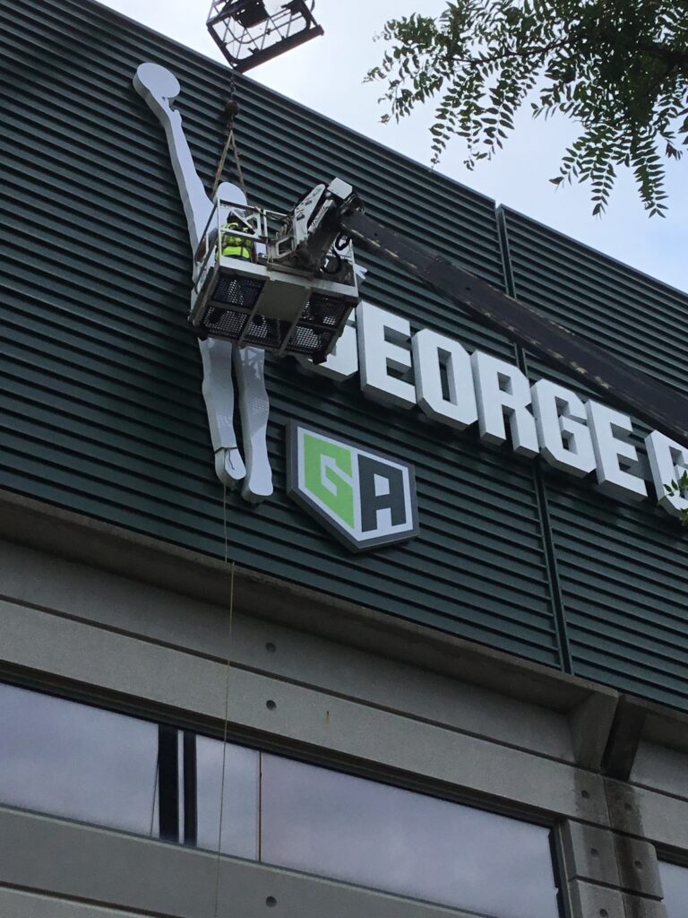 Crane installing new logo signage on the building